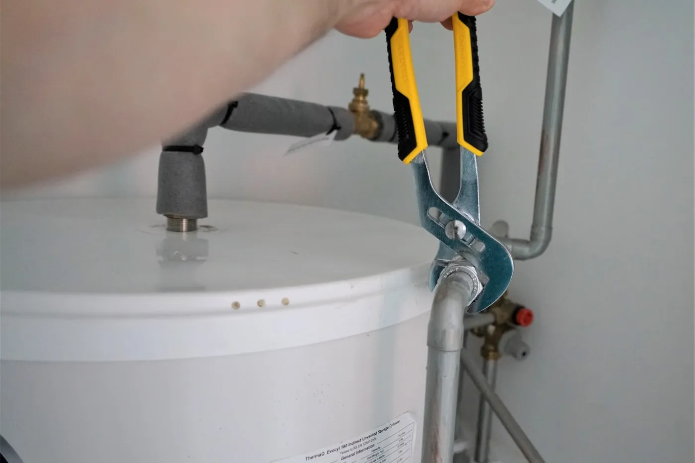 Raccords en sortie de chauffe-eau, pince multiprise serrée sur l’écrou du groupe de sécurité