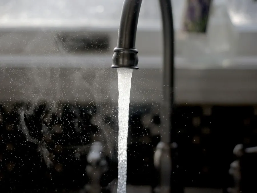 Filet d’eau tombant d’un mitigeur de cuisine, gouttes en suspension au-dessus de l’évier