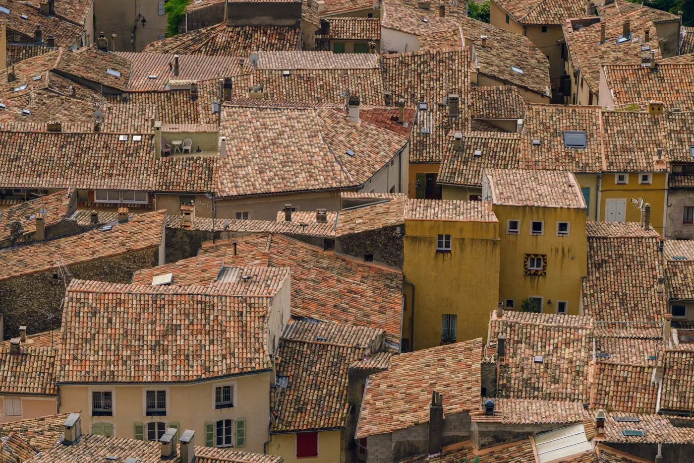Toits de tuile canal serrés les uns contre les autres, façades ocre et volets clos